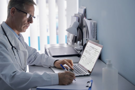 A doctor writing out a prescription on a laptop