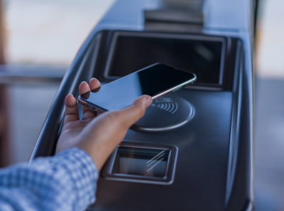 A person using a phone to pay for transport via NFC
