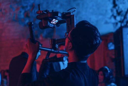 A cameraman in a black shirt records a video