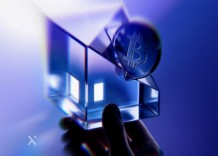 A hand holds a glass cube emitting a soft blue light, showcasing its transparent edges and illuminated interior.