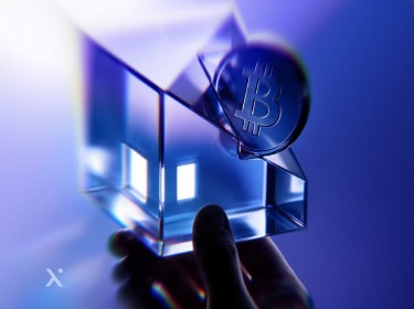 A hand holds a glass cube emitting a soft blue light, showcasing its transparent edges and illuminated interior.